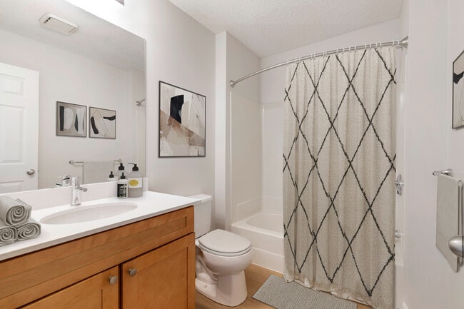 Renovated Package I bath with white quartz countertops, maple cabinetry, and hard surface flooring