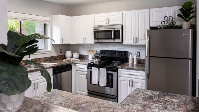 Cook in style with a fully equipped kitchen featuring stainless steel appliances, granite-style countertops, and ample cabinetry. - Harper Grand