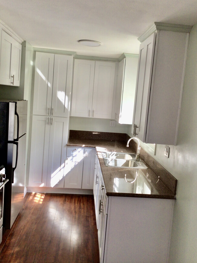 Newly remodeled kitchen with stainless steel appliances and white cabinetry - 7037 W Manchester Ave Apartments