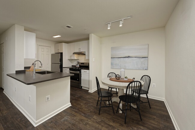 Renovated Package II kitchen and dining area with white cabinetry, dark grey laminate countertops, and stainless steel appliances, and hard surface flooring