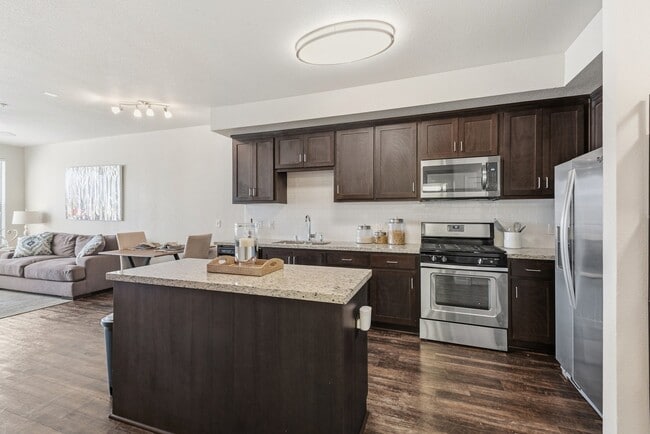 Aspire Apartments Tracy CA A modern kitchen with dark wood cabinets and stainless steel appliances.