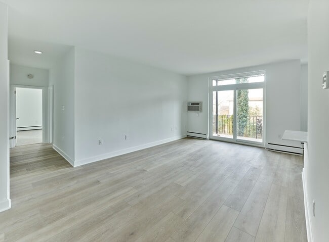 Open and airy living space with large windows and balcony access at Crestwood Apartments in Wayne, PA