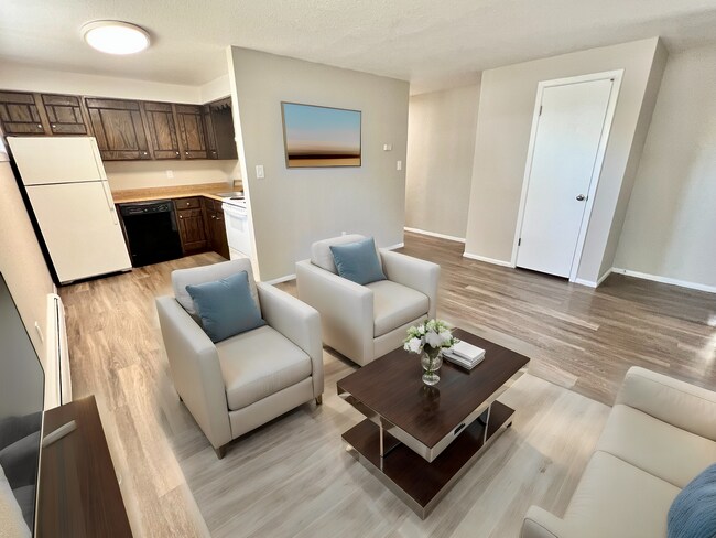 Chic open-concept living room with modern furniture, bright kitchen, and elegant wood flooring. - 591 West Prentice Avenue