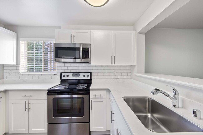 Prepare your favorite meals in a sleek, modern kitchen featuring stainless steel appliances and clean, contemporary finishes. - Windsor Juanita Bay Apartments