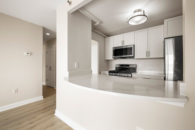 Modern kitchen with sleek statuario quartz countertops, white cabinets, stainless steel appliances, and gas stove for a sophisticated look at Parkside Place, apartments in Cambridge, MA - Parkside Place