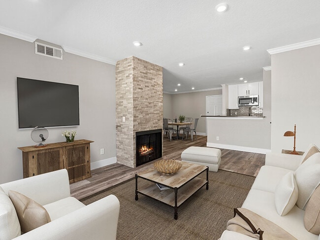 Sala de estar con detalles en piedra con chimenea y televisor.