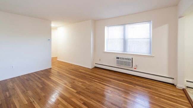 Step into the inviting ambiance of Dorchester House Apartments. This spacious living area boasts beautiful hardwood floors and abundant natural light, perfect for making lasting memories. Schedule your visit today to explore your future home! - Dorchester House