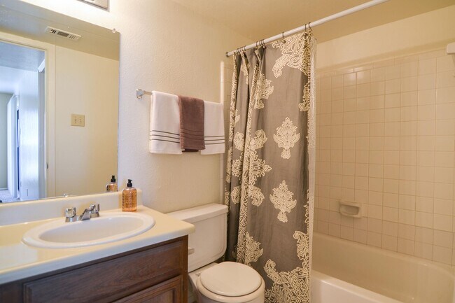 Un baño con bañera, armario de almacenamiento y un amplio espejo sobre el lavabo. - Wildflower