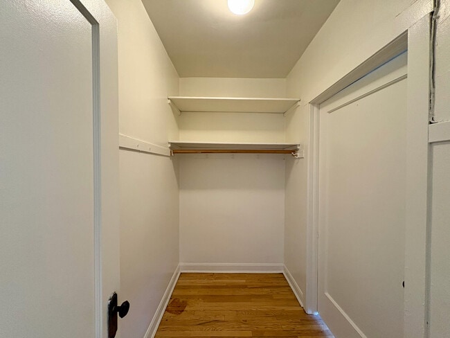 Spacious walk-in closet with built-in wooden shelving and elegant hardwood flooring.