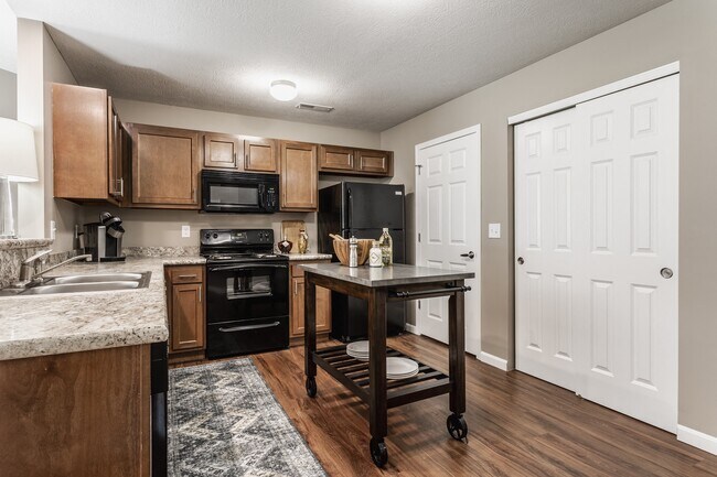 Experience a beautifully designed kitchen with a central island, sleek black appliances, granite countertops, and warm wooden cabinetry—perfect for cooking and entertaining.