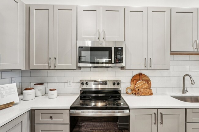 A modern kitchen with a stove, microwave, and ample cabinets.