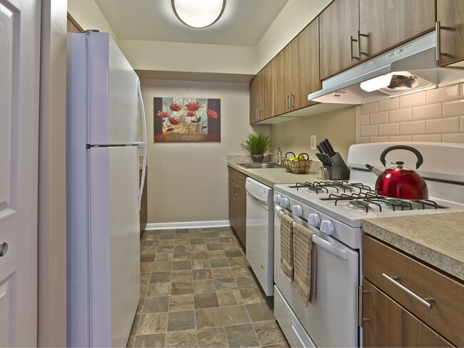 Stylish renovated kitchen at Haynes Run Apartments featuring wood cabinetry, gas cooking, a tile backsplash, and updated countertops for a modern living experience.