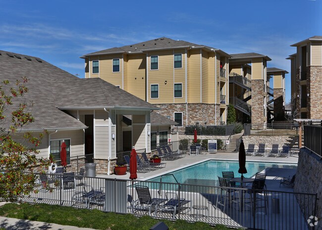 Expansive poolside with patio seating and landscaped backdrop.