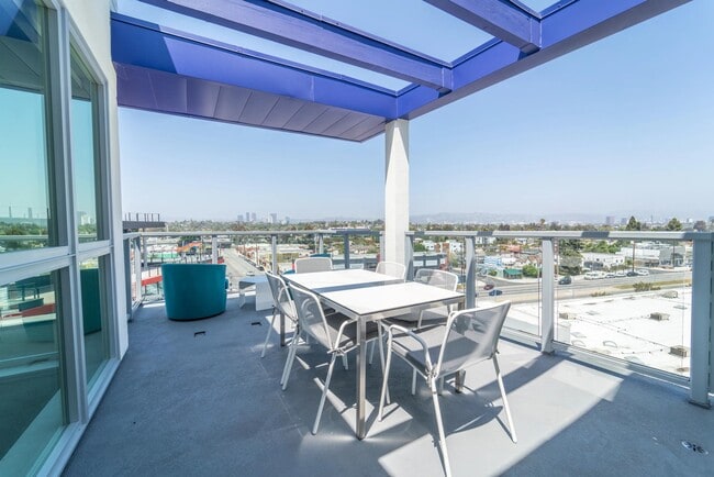 Covered rooftop terrace with dining seating, glass railings, and expansive city views that create an inviting setting for outdoor meals and conversation.