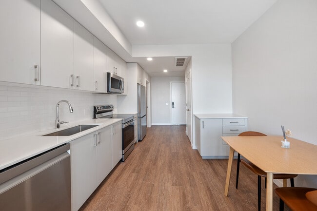 Finish Scheme II kitchen with light cabinetry, eggshell quartz countertops, white tile backsplash and stainless steel appliances.