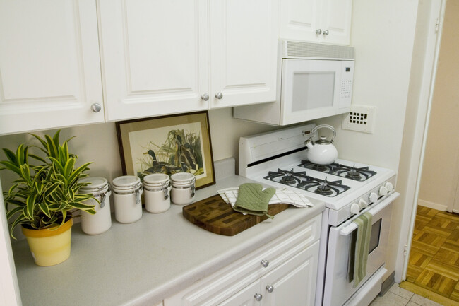 Kitchen with white countertop, white cabinetry, white appliances and hard surface flooring - eaves Glover Park Apartments