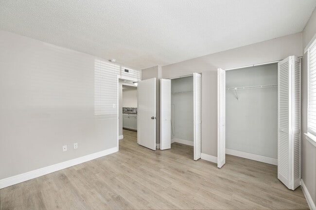 Dormitorio luminoso y espacioso con elegantes suelos de madera, amplio espacio de armario y luz natural que se filtra a través de grandes ventanales.
