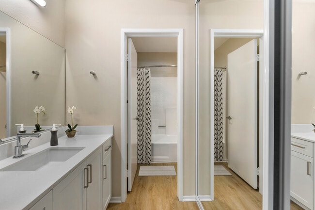 Renovated Package I bath with white quartz countertops, white cabinetry, and hard surface flooring - Avalon Burbank