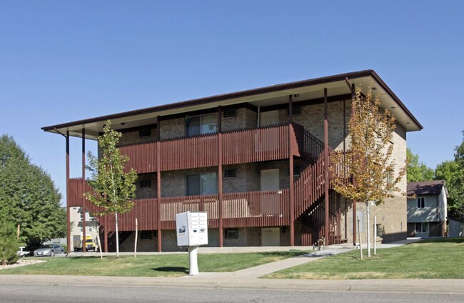 Charming three-story apartment building with brick exterior and wooden accents, nestled in a lush green environment.