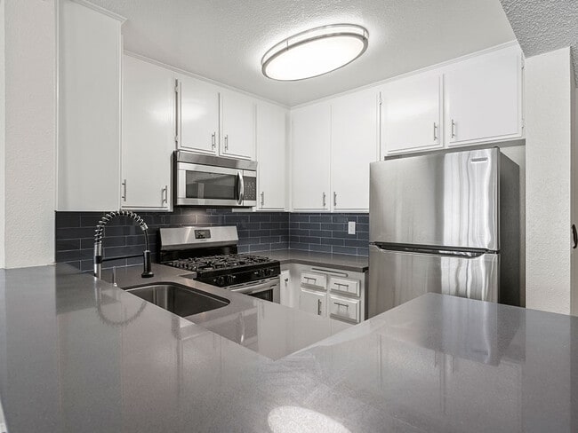 Kitchen with stainless steel oven, microwave, and fridge.
