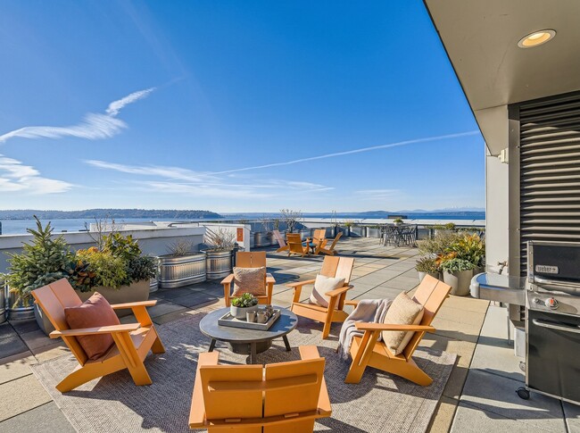 Rooftop amenity deck at 306 Queen Anne in Seattle, featuring outdoor lounge seating, a barbecue grill, and Puget Sound views.