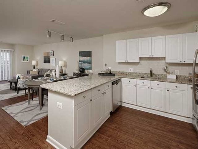 Open concept kitchen with white cabinetry, cream tile backsplash, stainless-steel appliances, granite countertops and hard surface flooring