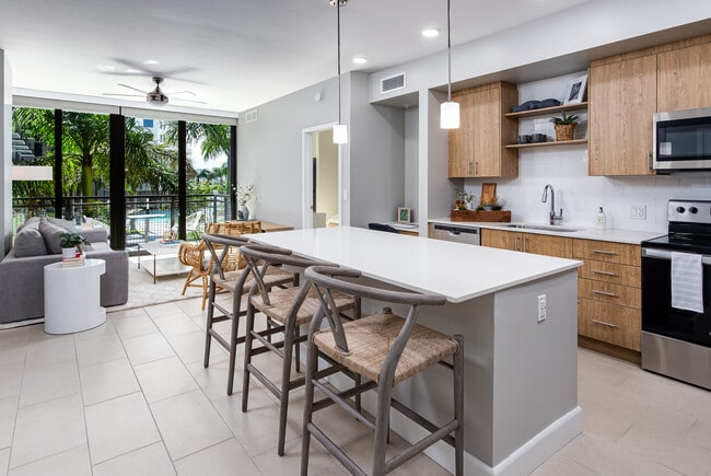 Open concept kitchen with quartz countertop, island, stainless steel appliances and tile backsplash