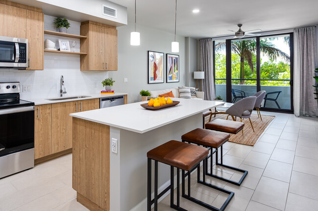 Open concept kitchen with quartz countertop, island, stainless steel appliances and tile backsplash - Avalon Doral Apartments