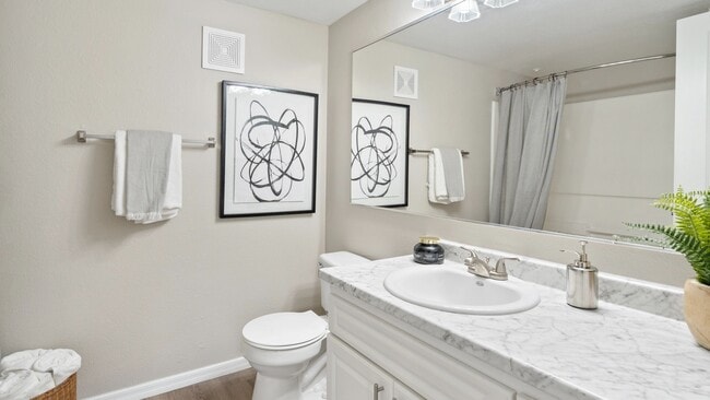 Enjoy a modern and stylish bathroom featuring a marble countertop, sleek fixtures, and a large mirror.