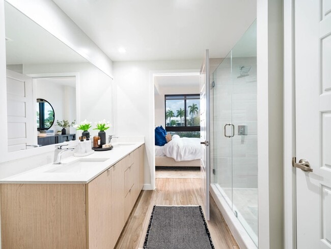 Spa-inspired bathroom design features clean lines, warm wood cabinetry, and glass-enclosed showers—bringing a calm, coastal feel to Modera Aventura homes.