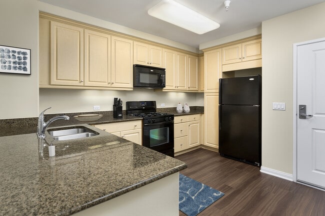 Classic Package I kitchen with black appliances, brown speckled granite, oak cabinetry, and hard surface flooring