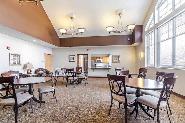 Inviting communal area featuring elegant round tables, plush seating, and a cozy kitchenette under warm lighting.