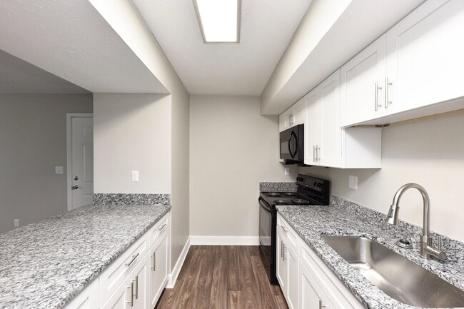 Kitchen with granite counters, black appliances, and modern cabinetry