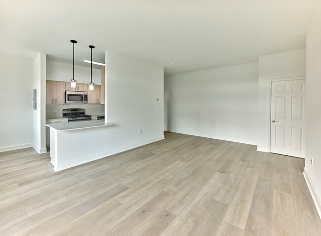 Open-concept floor plan with modern kitchen and wide plank flooring at Crestwood Apartments in Wayne, PA