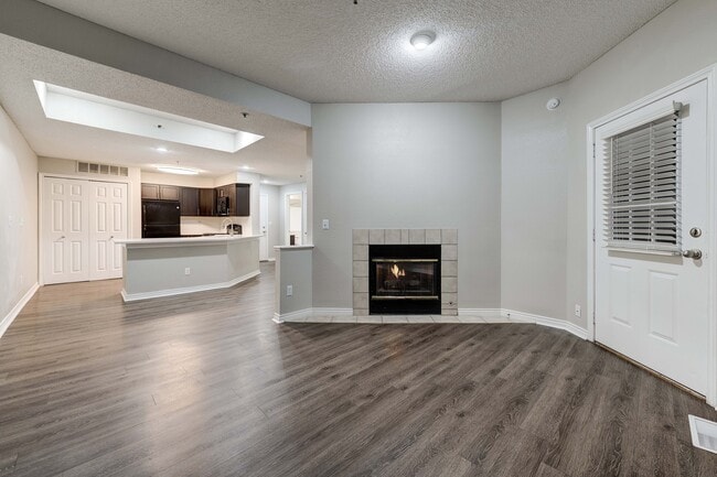 Inviting open-plan living area showcasing elegant wood flooring, a cozy fireplace, and a modern kitchen with dark cabinetry.