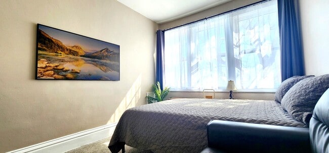 Primary Bedroom -Enjoy a 55” Samsung Frame TV and ample natural light through the oversized windows. - 822 E 4th St Unit #1