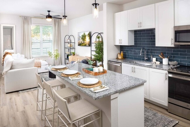 Experience seamless living with open-concept designs, merging kitchen and living spaces. - Windsor West Plano Apartments