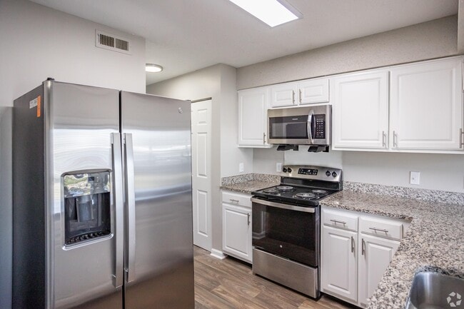 Cocina con mostradores de granito, gabinetes modernos y electrodomésticos de acero inoxidable. - Marina Pointe