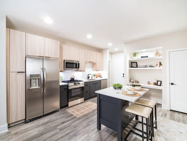 A light-filled kitchen with an oversized island, open shelving, and clean-lined finishes that support everyday cooking and casual dining. - Modera Westside Trail