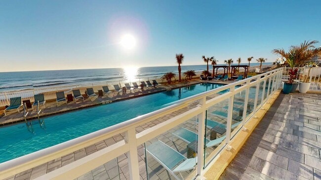 Lujosa piscina frente al mar con tumbonas, con vista al océano al amanecer. - Triton Cay - Daytona Apartments