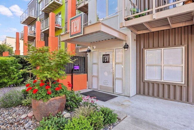 Secure building entrance at REV Fremont in Seattle, highlighted by colorful architectural accents and front landscaping.