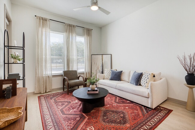 Bright living room featuring a large window and ceiling fan with lighting at Mesquite Trails at Broo