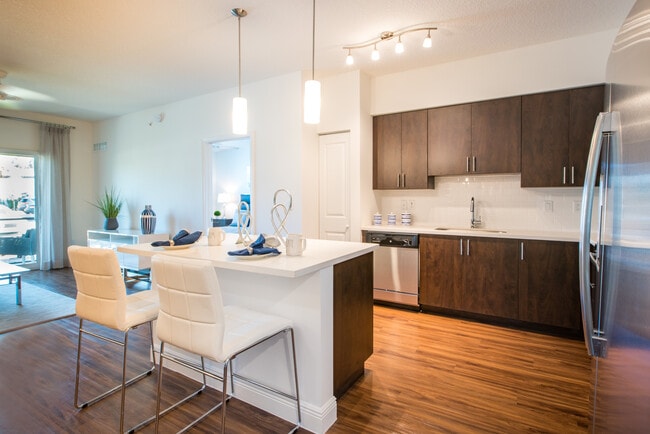 Kitchen with oak cabinetry, white countertops, white tile backsplash, and stainless steel appliances - Avalon Miramar Apartments