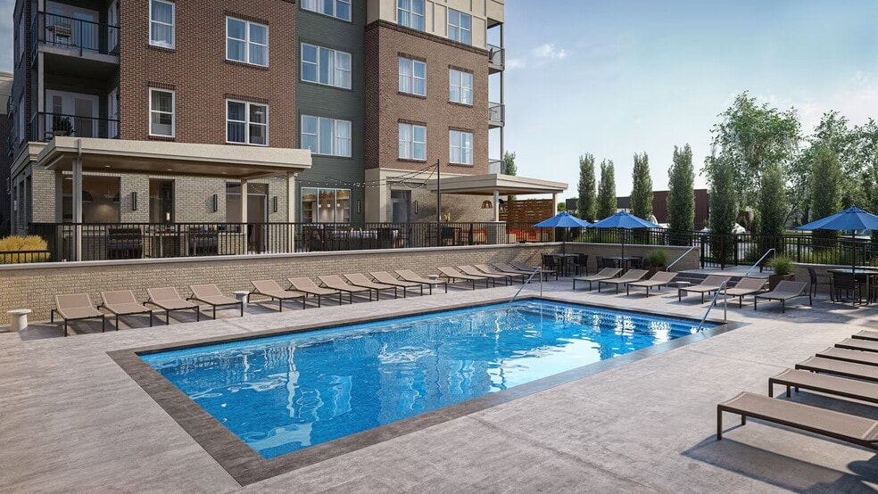 Resort-style pool with lounge seating and umbrellas at Trail House apartments in Norwood.