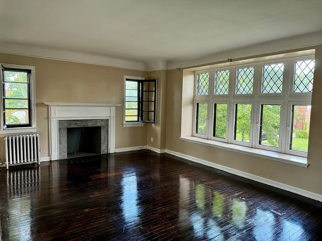 Large living room with hardwood floors, decorative fireplace, and oversized windows. - 3682 Glencairn Road Unit Upstairs