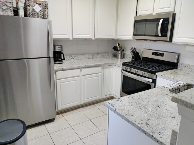 Kitchen with granite countertops and stainless steel appliances. - 11338 Westbrook Mill Ln Condo Unit 301