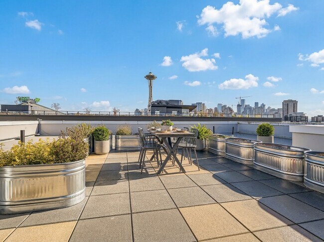 The rooftop deck at 306 Queen Anne offers outdoor dining seating, planters, and direct views of the Space Needle.