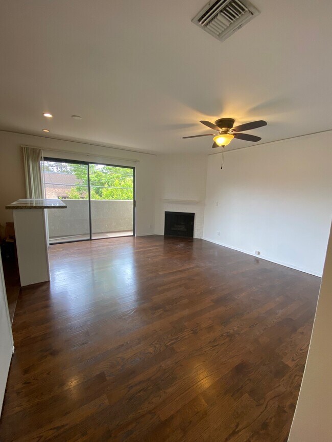 Living room with balcony & gas fireplace and ceiling fan light - 10330 Riverside Dr