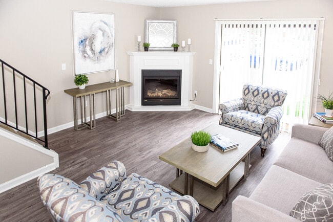 Living area with faux wood flooring, sliding doors to patio, and fireplace (in select uniits) - Chartwell Townhouse Apartments