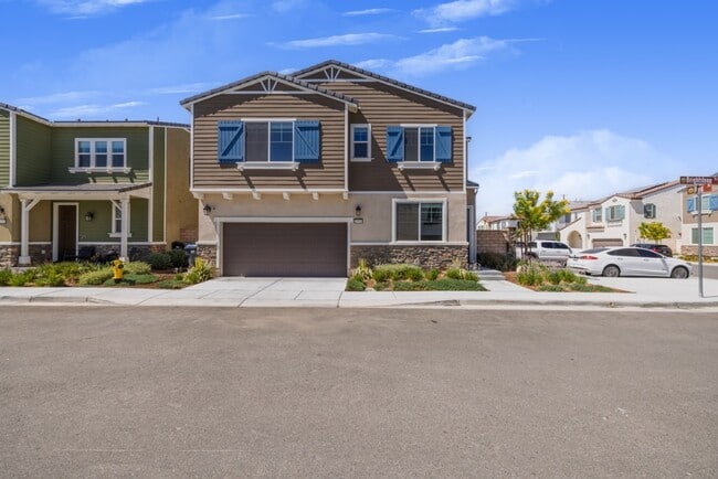 Vista frontal de una moderna casa de dos plantas con una amplia entrada para vehículos, jardín ajardinado y grandes ventanas. - 26549 Brightstone Dr